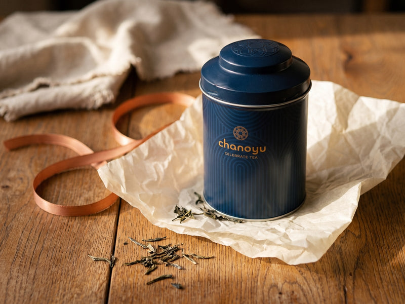 Une boîte Chanoyu posée sur du papier de soie, avec un ruban cuivré
